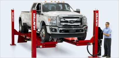 Hunter L451 four post alignment rack and lift with a heavy duty truck lifted and employee operator standing to the side
