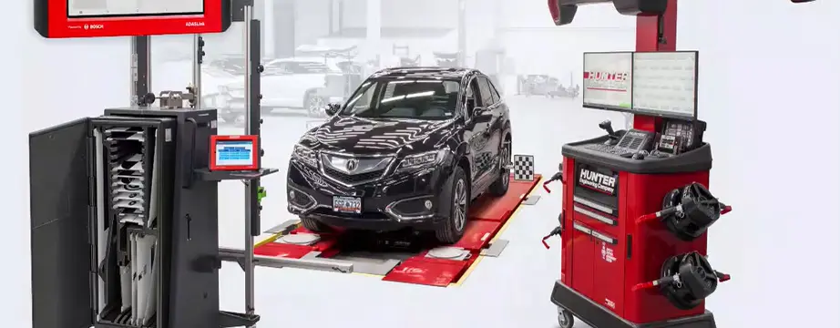 Vehicle in tire shop sitting on a Hunter wheel alignment system pad and Hunter system cart next to the car.