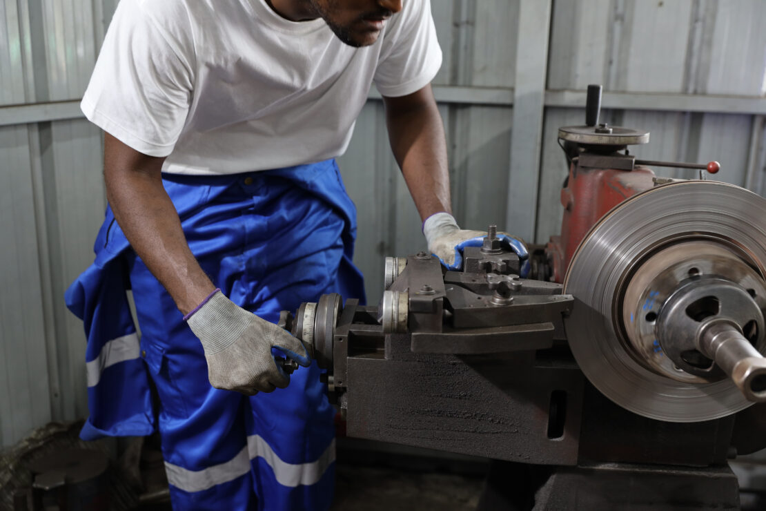 A technician works on a rotor using a bench brake lathe