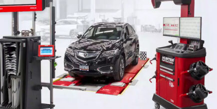 Vehicle in tire shop sitting on a Hunter wheel alignment system pad and Hunter system cart next to the car.